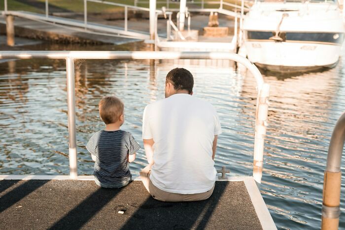 Father and son sitting by the water, reflecting on life and what became of their school bullies over time.