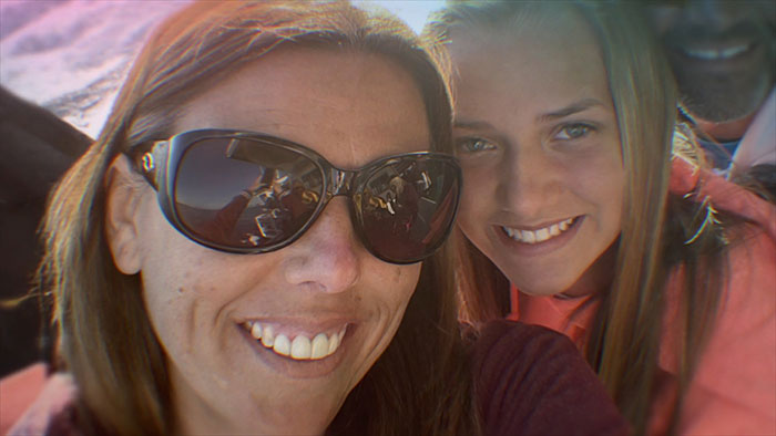 Smiling woman wearing sunglasses and young girl in a close selfie, relating to mom secretly tormenting daughter case.