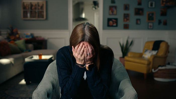 Woman sitting in a chair covering her face, expressing emotional distress about family secret and broken person reaction.