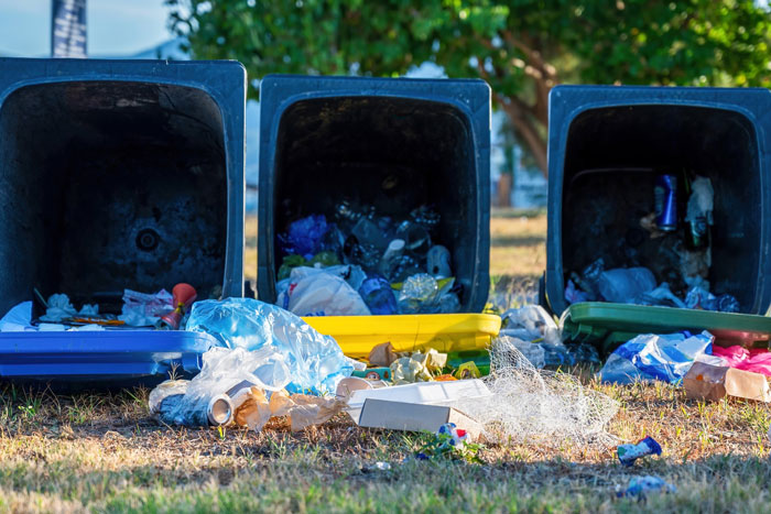 Three overturned garbage bins with trash spilled on the ground, illustrating bins left on neighbor’s driveway being kicked back. Three overturned garbage bins with trash spilled on the ground, illustrating bins left on neighbor’s driveway being kicked back.