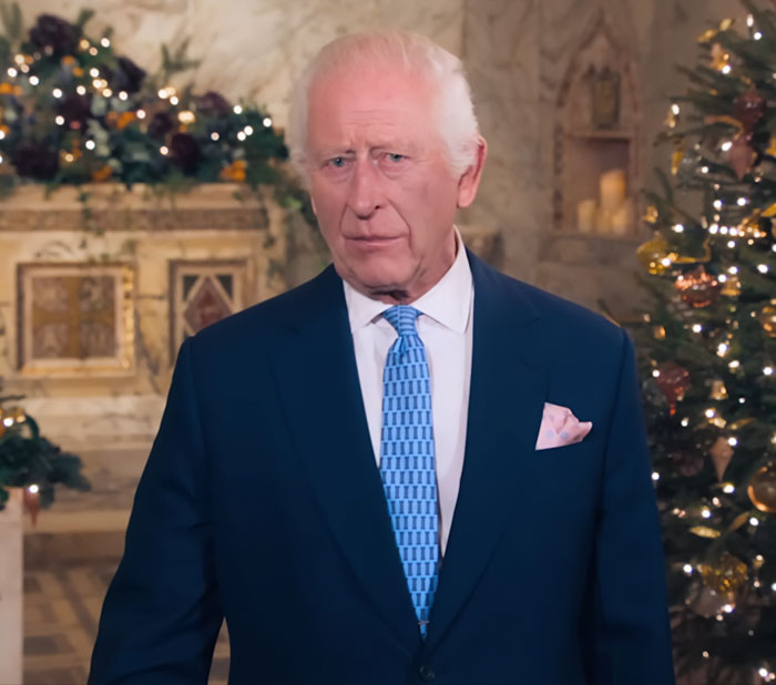 King Charles in a formal suit, delivering an emotional update on his incurable cancer in a decorated interior setting.