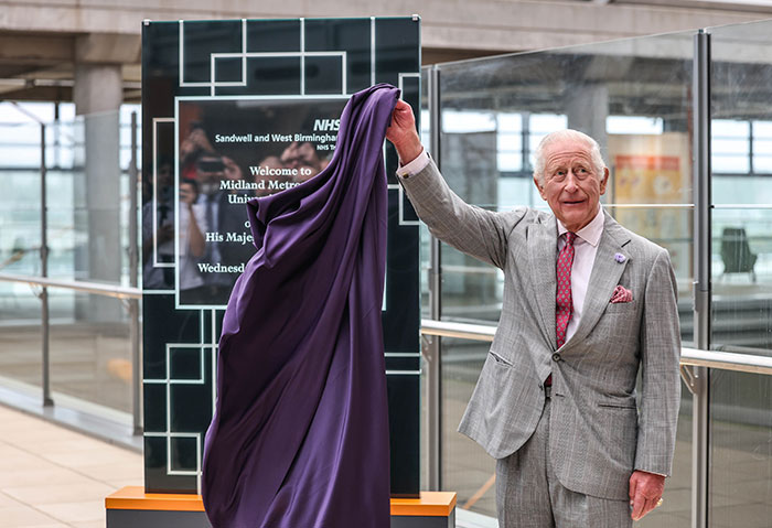 King Charles unveiling a plaque at Midland Metropolitan University Hospital, sharing emotional update on incurable cancer.