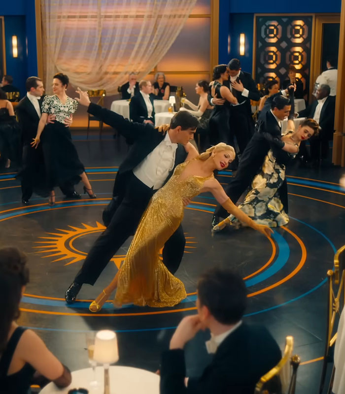 Couples dancing elegantly in a ballroom setting with a woman in a gold dress resembling Jennifer Lopez or Gwen Stefani.