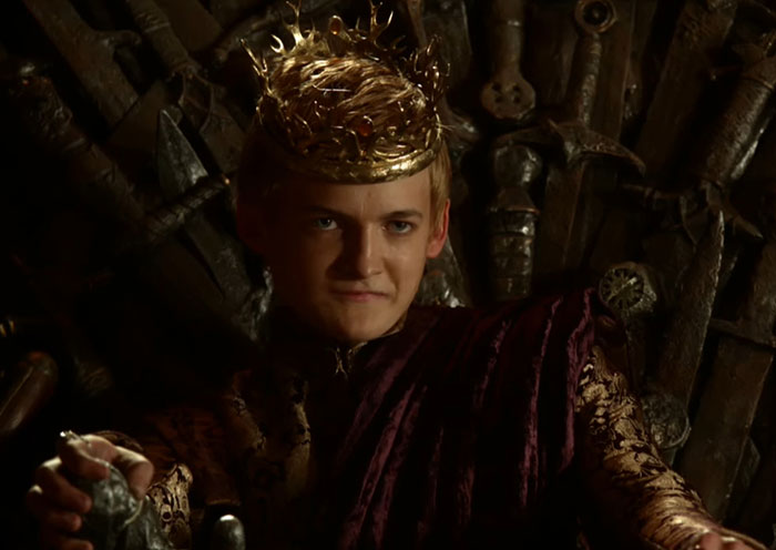 Actor wearing a crown and regal attire sitting on a throne, illustrating celebrities before fame and their early persona.