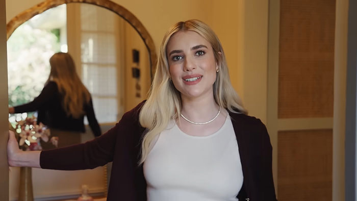 Young woman smiling indoors, sharing insights about celebrities before fame in a casual home setting.