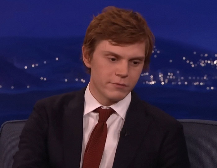 Young man with red hair in a suit and tie during a TV interview about people who knew celebrities before fame.