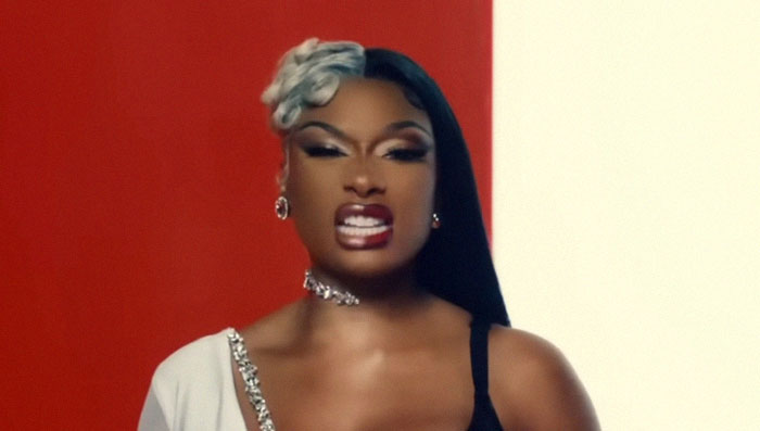 A confident woman posing against a red and white background, reflecting stories from people who knew celebrities before fame.