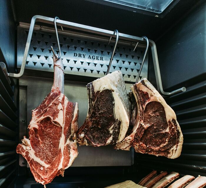Dry aged meat hanging in a restaurant cooler, highlighting unholy health violations witnessed by inspectors.