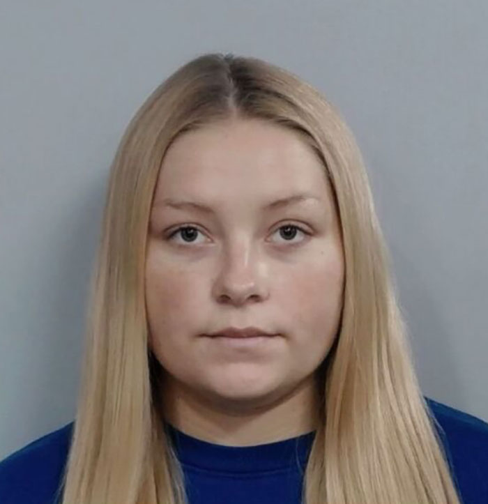 Young woman with long blonde hair in a blue shirt linked to social media posts about motherhood and tragic baby incident.