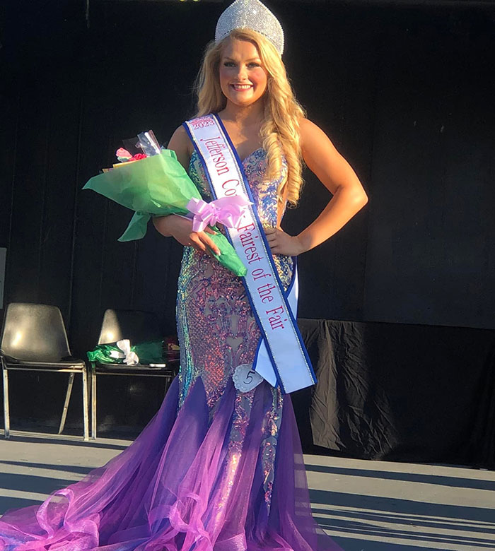Young woman in a purple gown and crown holding flowers, unrelated to social media posts about motherhood controversy.