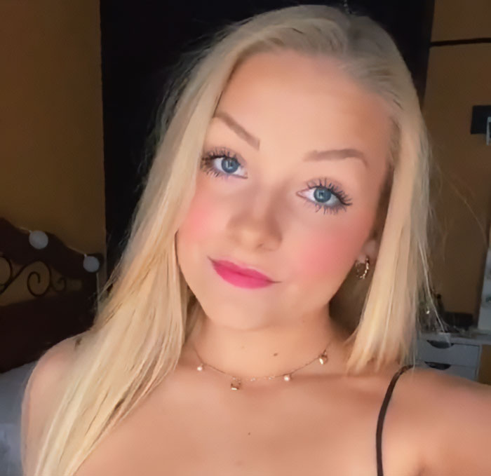 Cheerleader with blonde hair and blue eyes wearing a necklace, captured in a close-up selfie indoors. Cheerleader with blonde hair and blue eyes wearing a necklace, captured in a close-up selfie indoors.