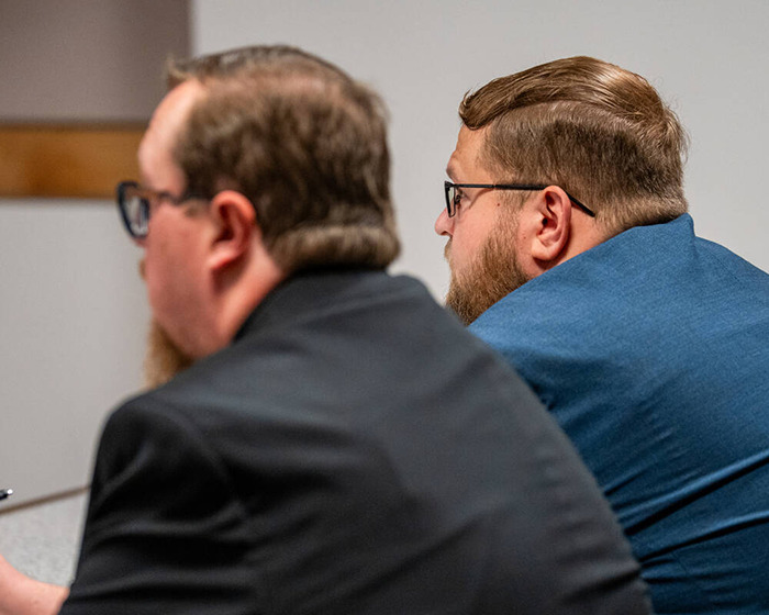 Two men with glasses seated in a courtroom setting, highlighting the man who accused mom of incest legal case.