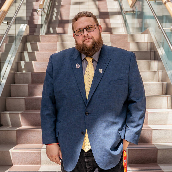 Man wearing glasses and blue suit standing on stairs, related to man declared legal father of his brother news.