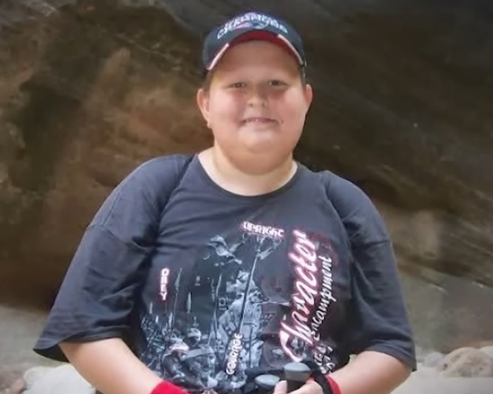 Young boy wearing a cap and black t-shirt outdoors, related to man declared legal father of his brother news.
