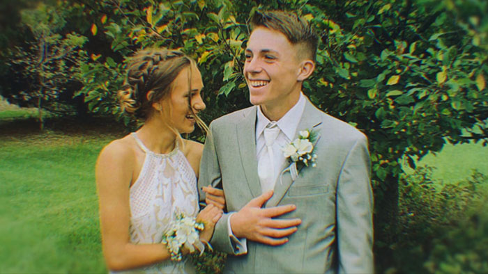 Young couple dressed for a formal event standing outdoors with greenery, capturing a joyful moment before sentencing news. Young couple dressed for a formal event standing outdoors with greenery, capturing a joyful moment before sentencing news.