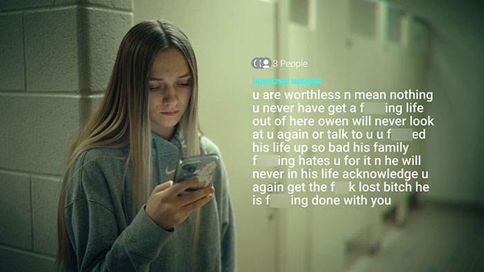 Teen girl reading hurtful anonymous texts on phone, illustrating impact of mom who sent lewd messages for a year. Teen girl reading hurtful anonymous texts on phone, illustrating impact of mom who sent lewd messages for a year.