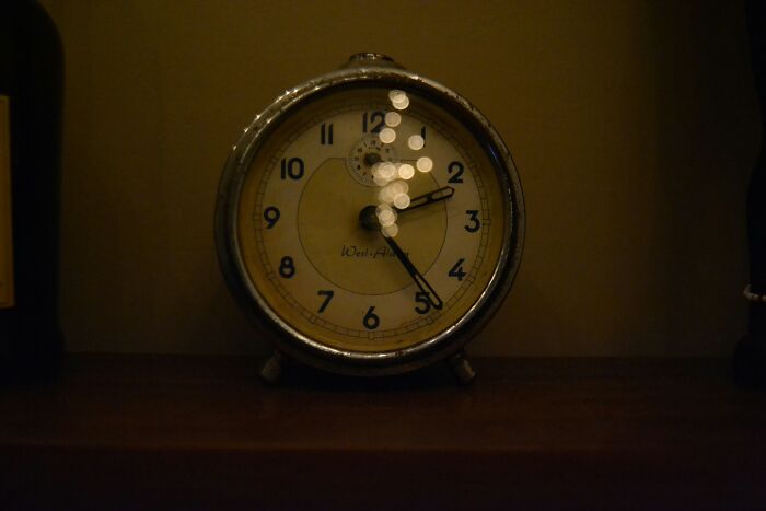 Vintage clock showing 2:25 on a dark wooden shelf, symbolizing trust your gut feeling and precognition concepts.