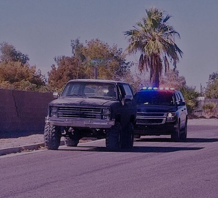 Police car with flashing lights behind an off-road vehicle on a suburban street, illustrating innocent people blamed by police.