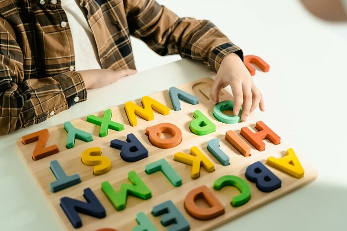 Child playing with colorful wooden alphabet puzzle, highlighting how folks incriminated themselves in dumb ways.