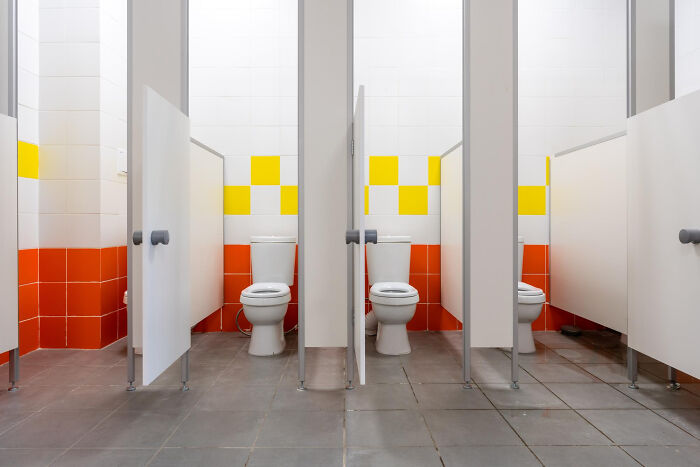 Public restroom stalls with toilets and colorful tiled walls, illustrating unexpected ways people incriminated themselves.