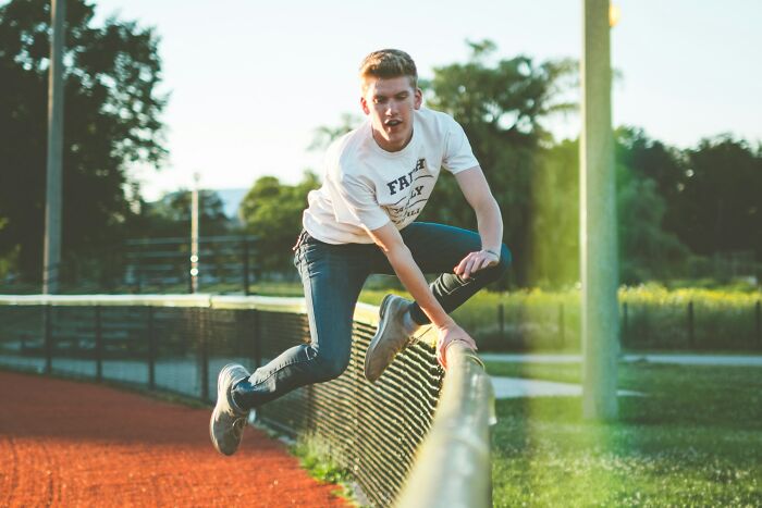 Young man climbing over a fence outdoors, illustrating risky behavior linked to how folks incriminated themselves.
