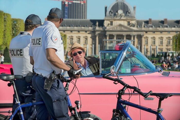 Two police officers on bicycles talking to a man in a vintage pink car, illustrating lawyers and cops cases.