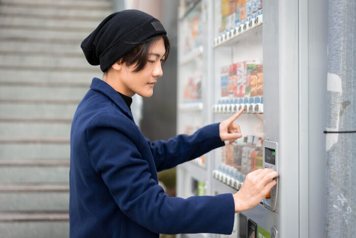 Young person using vending machine outdoors, illustrating lawyers and cops revealing dumb ways people incriminated themselves.