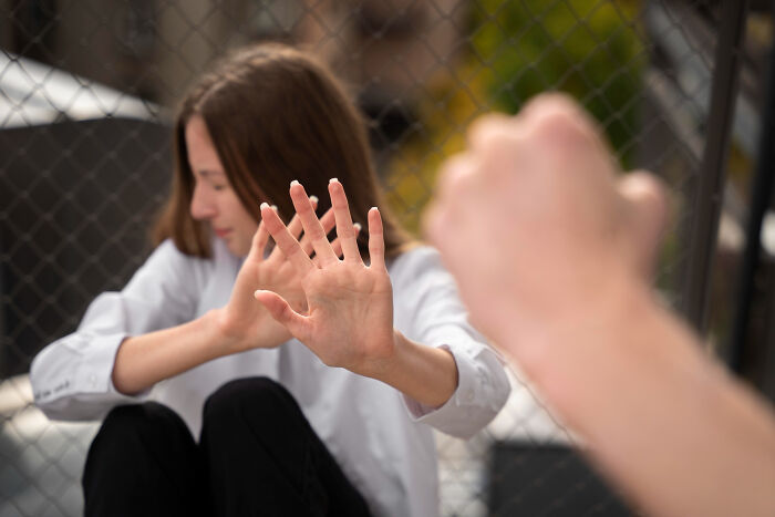 Young woman shielding herself with hands, illustrating reckless actions that lawyers and cops say incriminate people.