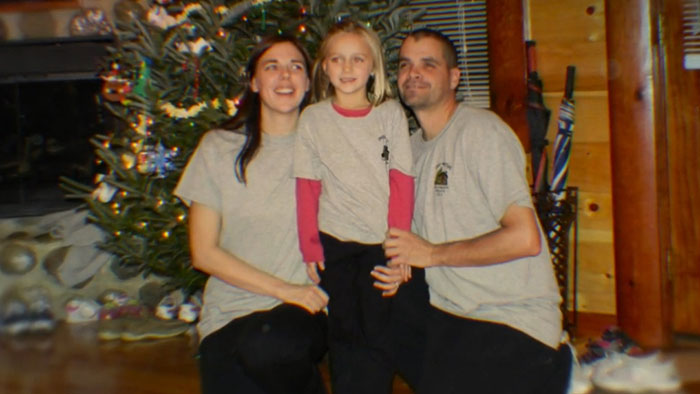 Family of three posing indoors near Christmas tree, illustrating a broken person and devastated dad's reaction to bullying secrets.
