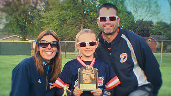Family of three wearing sunglasses posing outdoors with a young girl holding a sports trophy fed on that prosecutor keywords