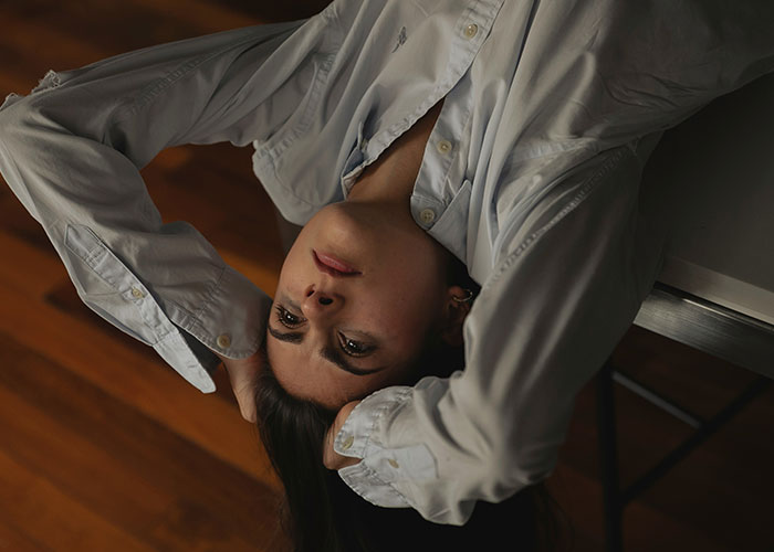 Young woman in a white shirt lying back with hands behind head, reflecting on interesting scientific facts that are eerie.