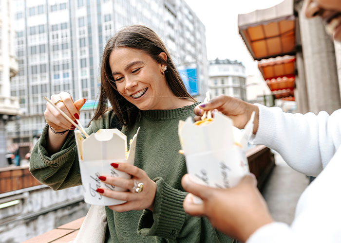 Two people enjoying street food outdoors, smiling and sharing interesting scientific facts that are also a bit eerie.