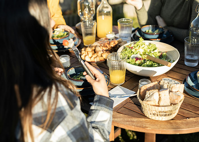 People enjoying a meal outdoors with fresh salad, bread, and drinks, illustrating interesting scientific facts and eerie curiosities.