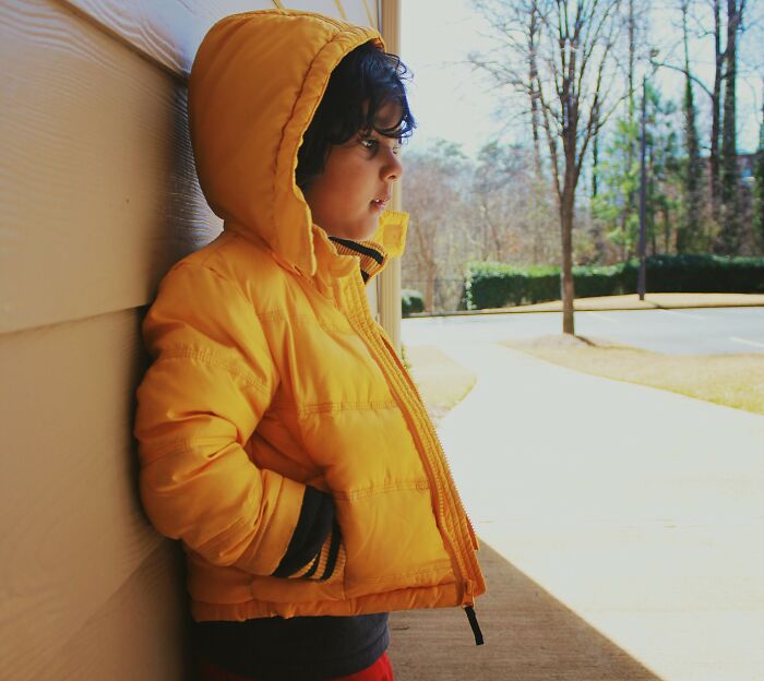 Child in a yellow jacket leaning against a wall, illustrating innocent people blamed by police in wrongful accusations.