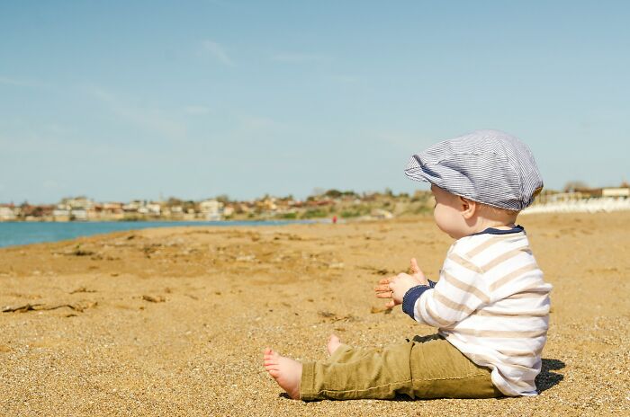 Toddler sitting alone on a sandy beach under a blue sky, illustrating signs a relationship isn’t going to last.