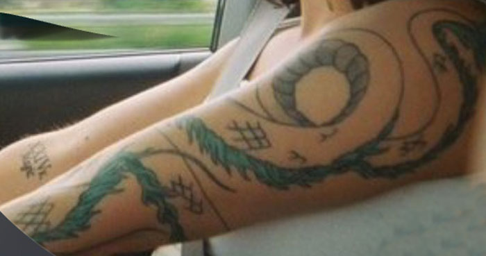 Arm tattoo featuring a green and black serpent with abstract patterns, perfect lying pick me girl tattoo inspiration design.