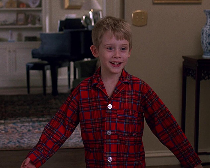 Macaulay Culkin as a child actor wearing red plaid pajamas in a home setting, related to John Candy and his father. Macaulay Culkin as a child actor wearing red plaid pajamas in a home setting, related to John Candy and his father.