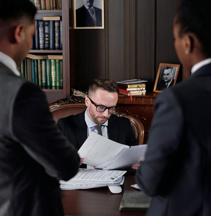 Man in a suit reviewing legal documents in an office, illustrating a man proven not guilty but facing consequences.