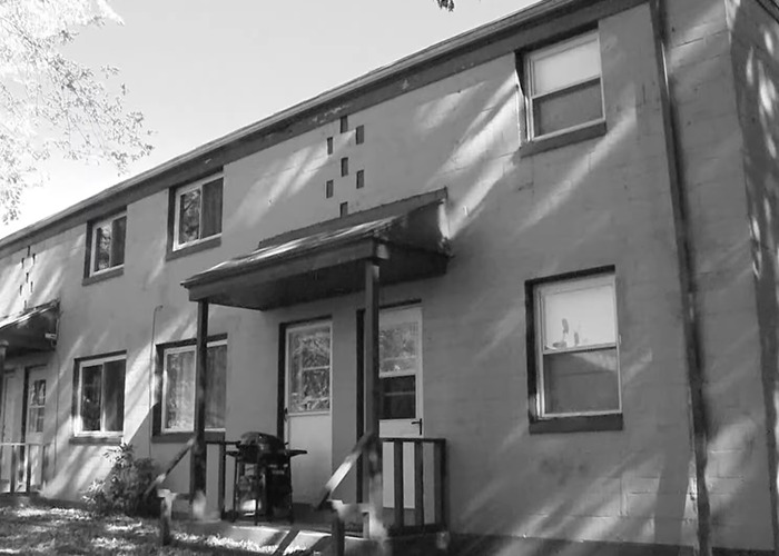 Exterior of a modest residential building in black and white, related to a police cold case solving after 52 years.