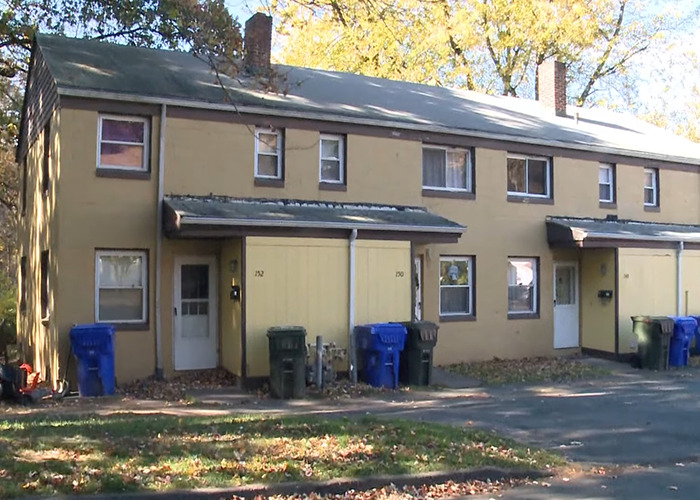 Yellow townhouse with garbage bins outside on a quiet street, related to a police cold case investigation after 52 years.