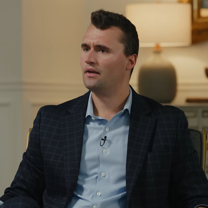 Man in blue shirt and checkered jacket speaking during an interview about Charlie Kirk bullying claims.