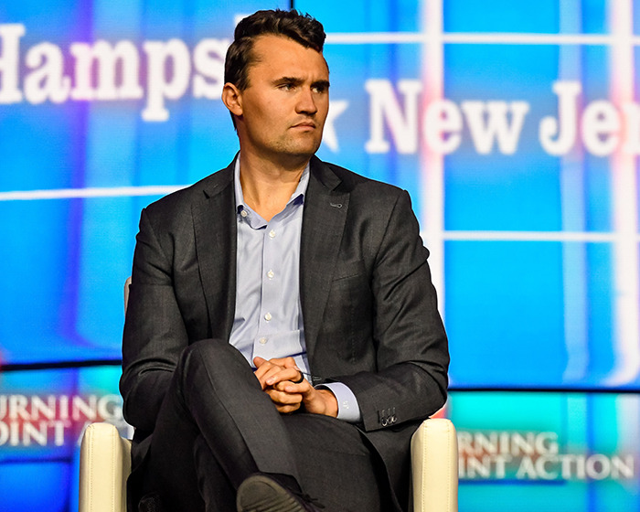 Man claims Charlie Kirk bullied him relentlessly in high school as he sits onstage in a dark suit during an event.