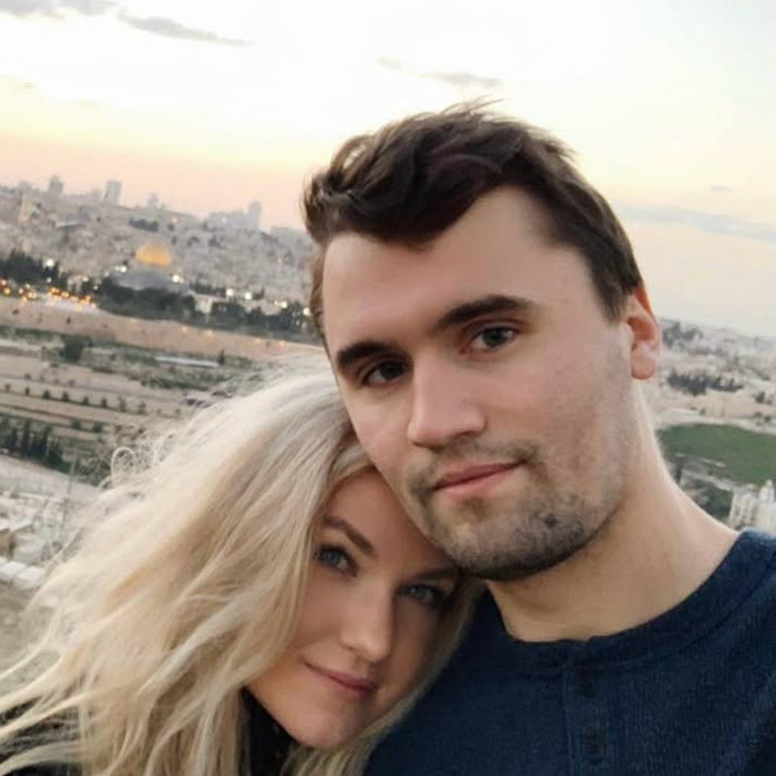 Man and woman posing outdoors with cityscape in background, related to Charlie Kirk bullying claims.