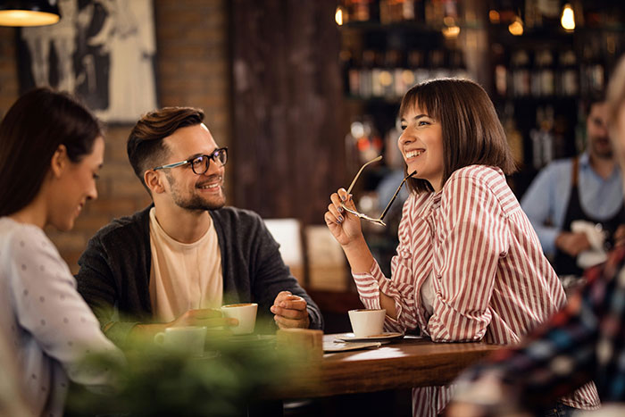 Man and woman engaging in a friendly conversation at a cafe, highlighting robotically calculated relationship choices.