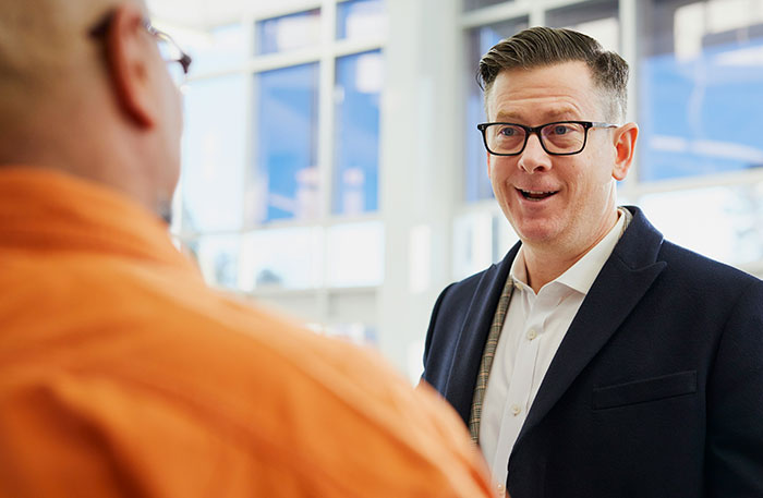 Man in glasses and suit engaged in serious conversation, depicting an employee going nuclear on manager over promised raises.