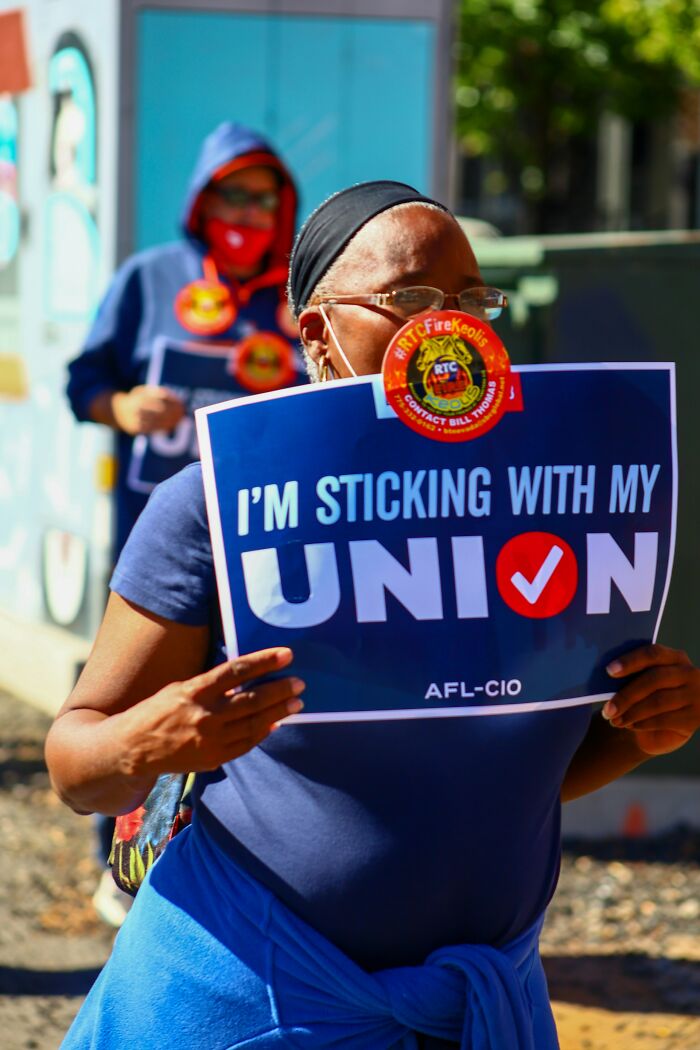 Person holding a union sign at a rally wearing a mask, representing dumbest and out of touch things people were told.
