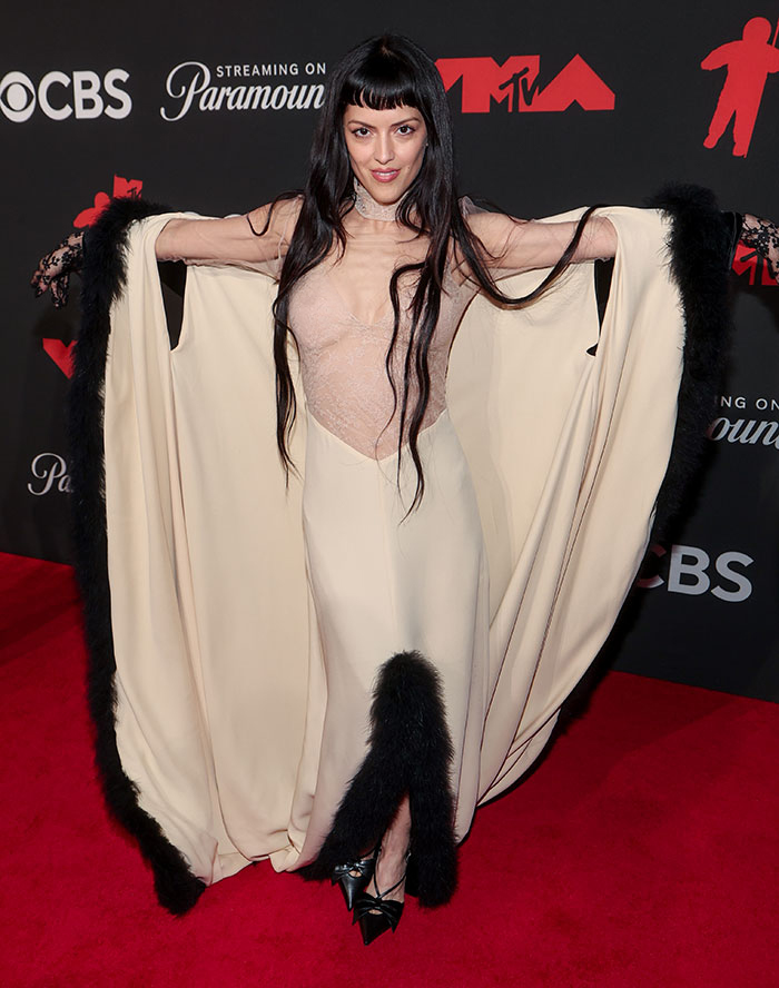 Female star in a beige and black feathered dress striking a pose at the 2025 Video Music Awards worst dressed stars event.