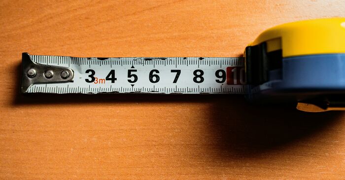 Yellow and blue tape measure extended on a wooden surface representing the next big thing that totally flopped concept.