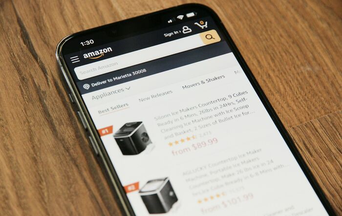 Smartphone displaying Amazon app showing appliances, illustrating Americans finding and using loopholes while shopping online.