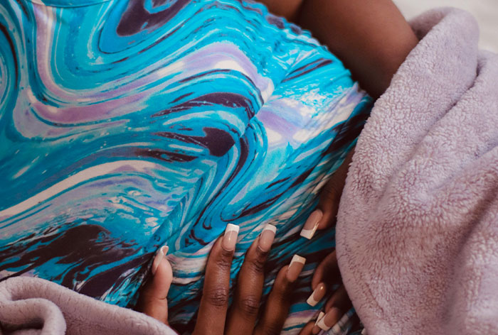 Pregnant woman lying down with hands on belly, illustrating downplayed medical conditions and procedures.
